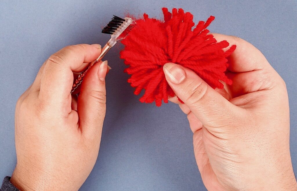 hands-brushing-yarn-how-to-make-pom-poms