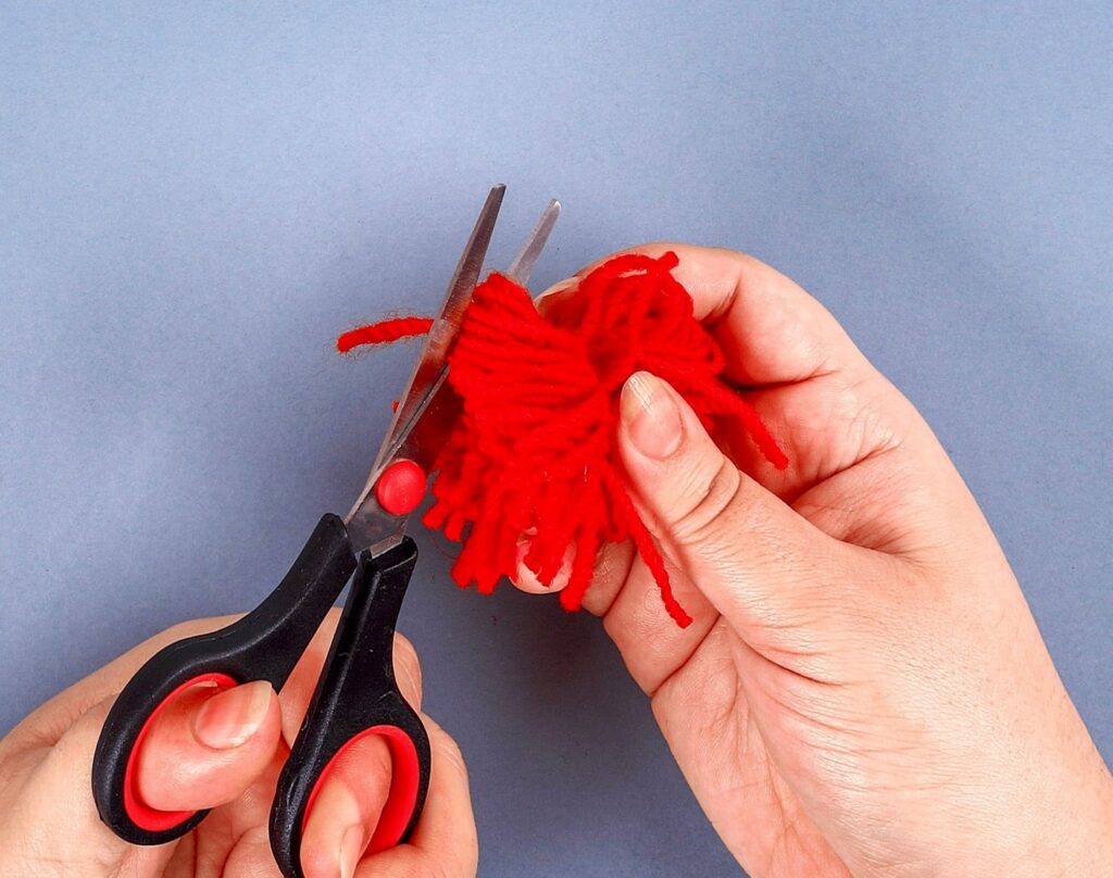 hands-cutting-yarn-how-to-make-pom-poms