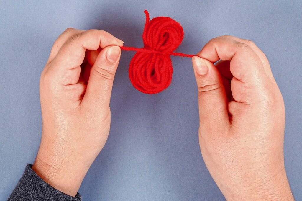 hands-tying-yarn-how-to-make-pom-poms
