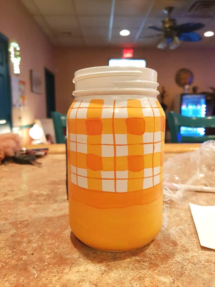 An adorable rustic plaid painted mason jar just in time for fall! Handpainted and colorful, this fun mason jar craft will look great where ever you put it. Use it as a vase for flowers, or in the center of your holiday table. The possibilities are endless. #CricutMade #Cricut #FallDIY #FallCrafts #MasonJar #MasonJarCrafts #CraftingWithMasonJars