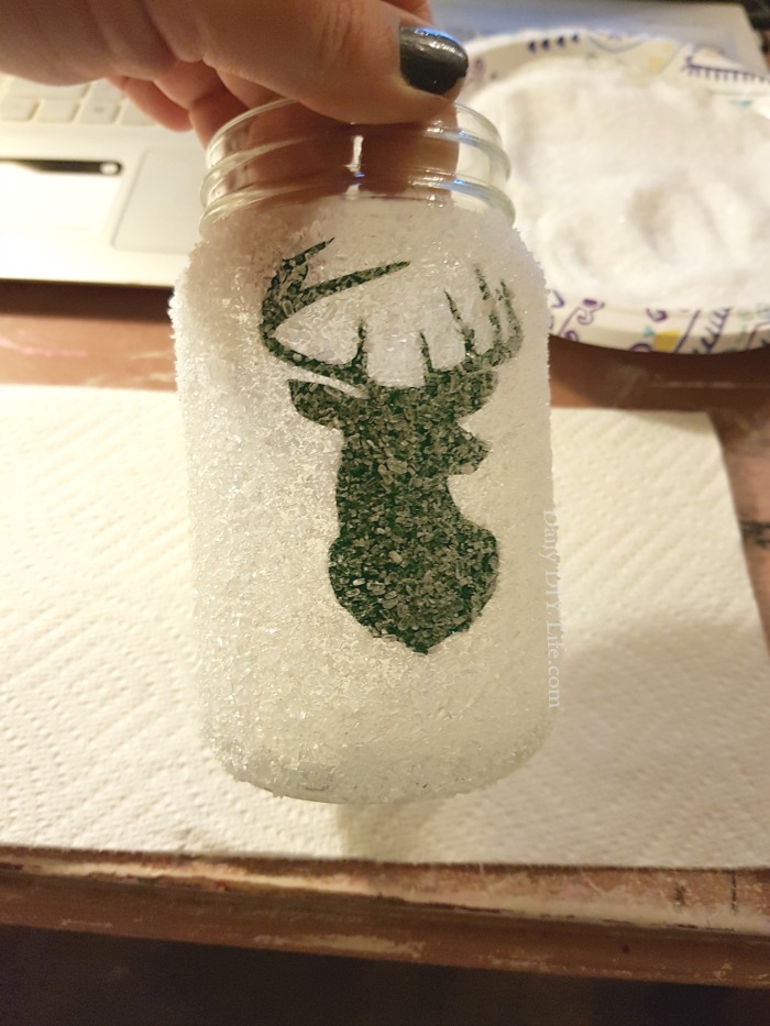A little bit rustic, a little bit glitzy. This super simple DIY Snow Covered Holiday Mason Jar will fit just right on your mantle or in the center of your table. Mix and match with your favorite holiday shapes or characters to match your decor. Even the kids can get in on this festive and easy christmas craft. #ChristmasCrafts #MasonJarCrafts #HolidayMasonJar #DIYCrafts #DIYChristmas #MasonJarChristmas #Cricut #CricutMade