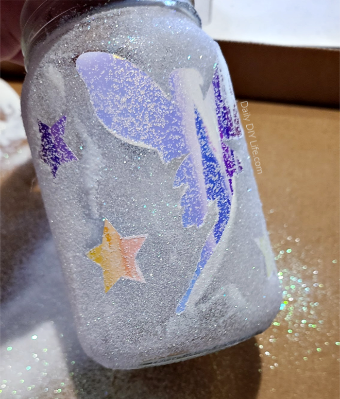 Whimsical DIY Glitter Fairy Jars have just the right amount of twinkle and imagination. We used Opal Vinyl for the accents so these glitter fairy jars look wonderful during the day as well as sparkle and shine all through the night. A fairy nightlight perfect for any room or campsite. Use a battery-operated set of twinkle lights, and you can take it anywhere, anytime. #Sponsored #Styletechcraftvinyl #StyleTechCraft #OpalVinyl #DIYGlitter #FairyCrafts #GlitterCrafts #DIYFairyGarden