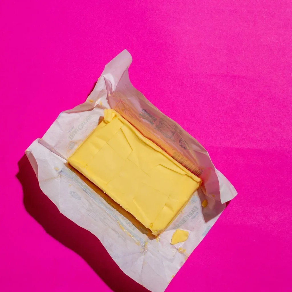 block of butter on pink background