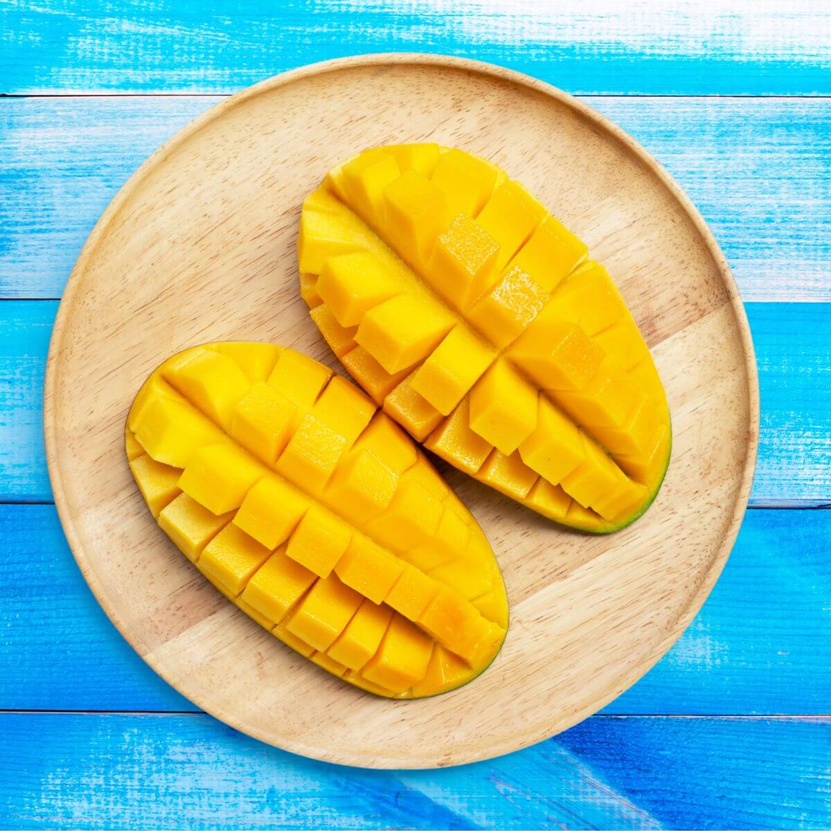 sliced open mango on wooden plate