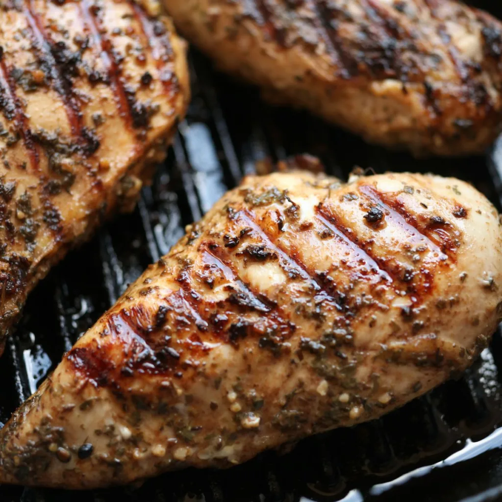 three seasoned chicken breast on a griddle