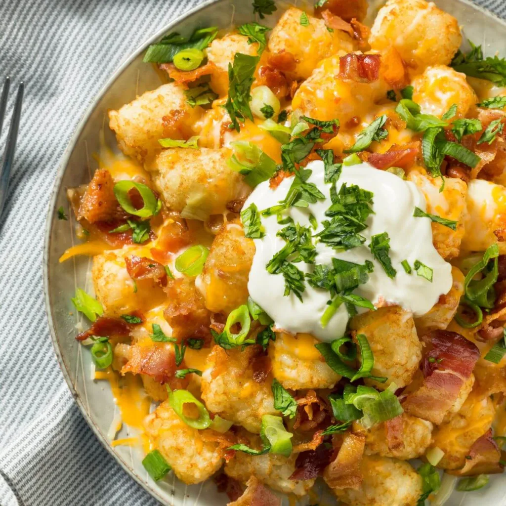 plate of loaded tater tot nachos with sour cream 